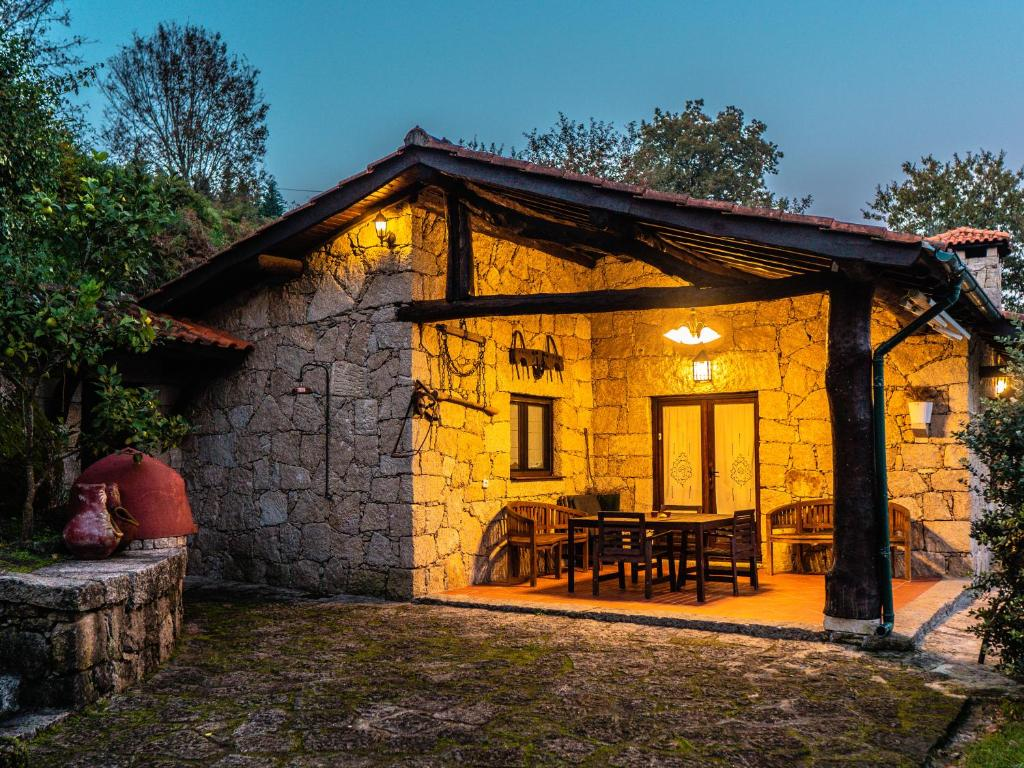 Exterior de A Casa da Terra al anochecer, con la fachada de piedra y el porche iluminados